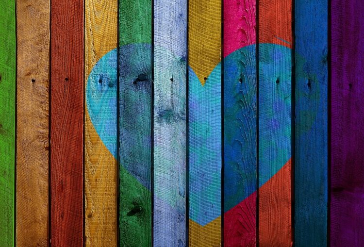 Vertical planks of wood painted different colours with a heart shape in the middle
